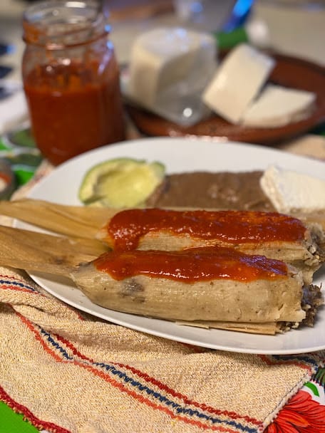 plated tamales with fresh salsa, beans and sliced avocado
