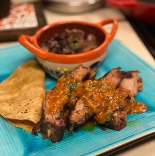 ribs plated with spicy salsa, tortillas and beans