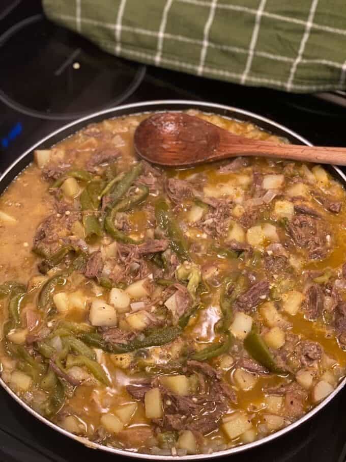 shredded beef and potato in large skillet, wooden spoon on the side
