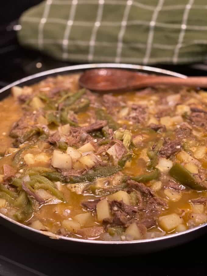 skillet on stove top with beef and potato and green chile