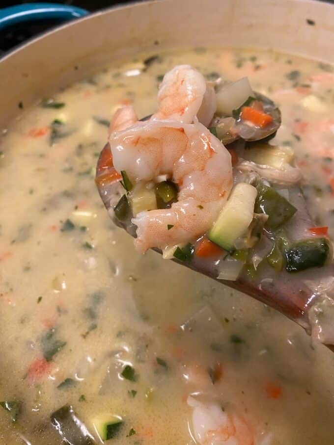close up of chowder on wooden spoon, big shrimp