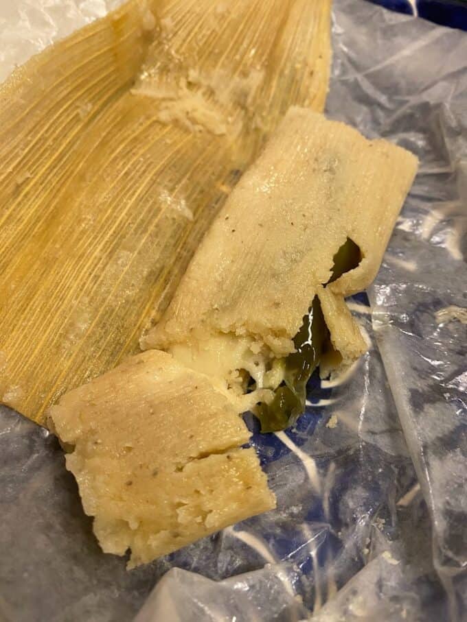 Fresh tamal out of the steamer unwrapped and cut open to expose cheese