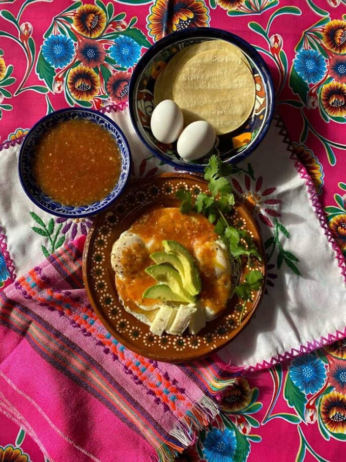 huevos rancheros plated with a salsa de mesa, avocado garnish