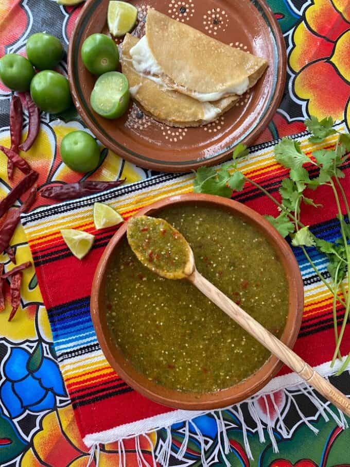 Salsa in large bowl with wooden spoon and simple corn tortilla quesadillas