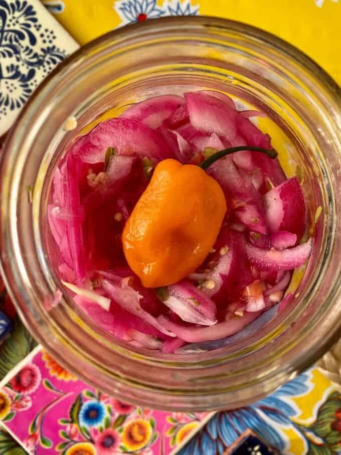 close up pickled red onions in an open glass jar