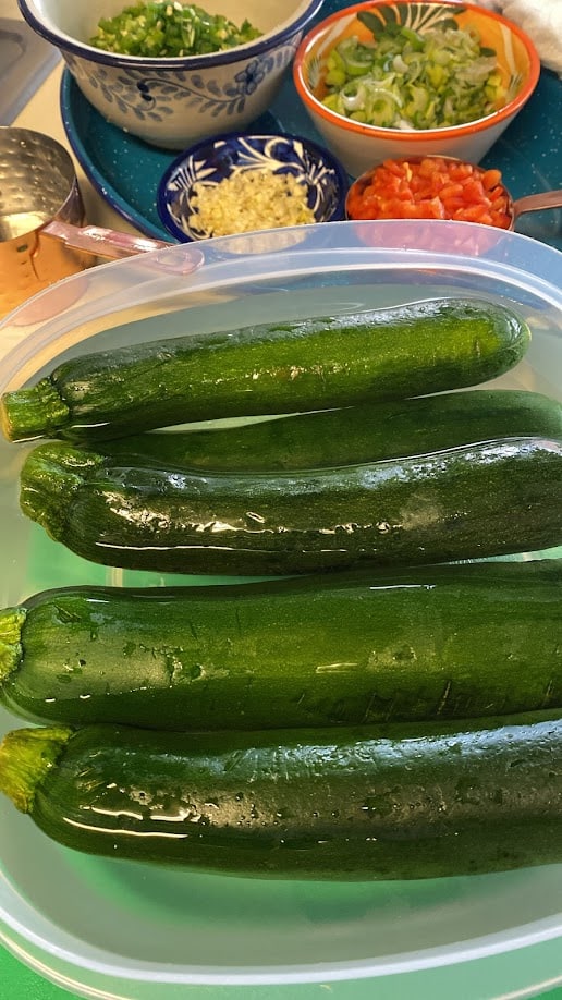 fresh zucchini in water with chopped ingredients for fritters