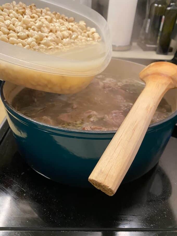 adding cooked hominy to pot
