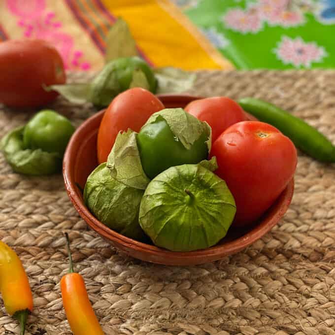fresh tomatoes, tomatillos and chile peppers in bowl