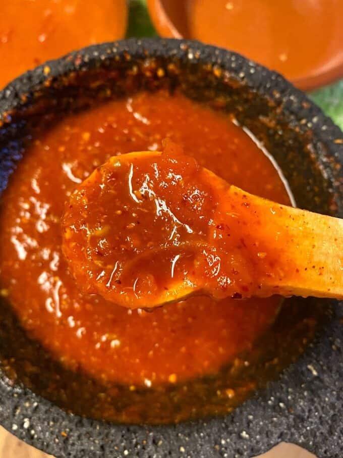 close up of molcajete salsa on a wooden spoon