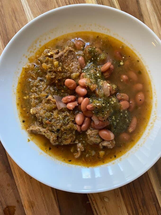 stewed beef in bowl with beans and salsa verde