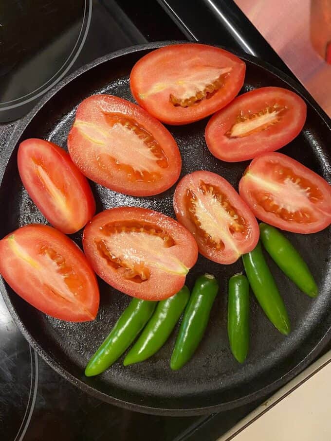 sliced tomatoes and whole serrano peppers on cast iron comal