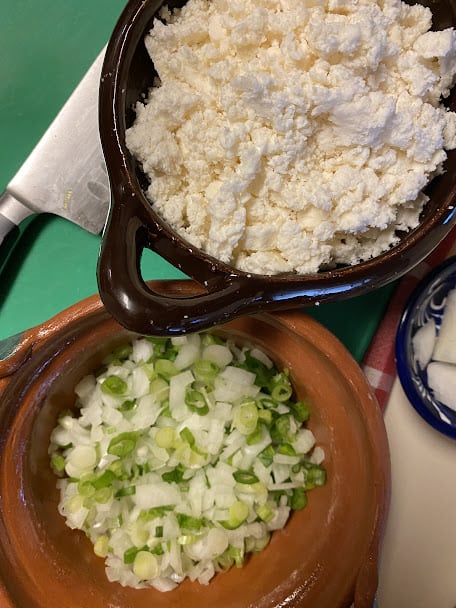 chopped onions and green onions in one bowl, crumbled queso fresco in another bowl