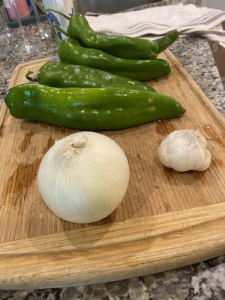 fresh green chiles, onion and garlic on cutting board