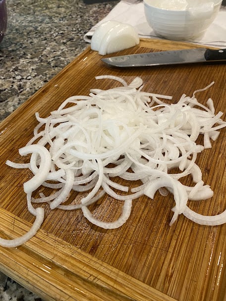 thinly sliced onion on cutting board