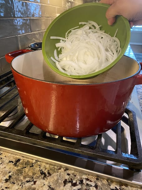 adding onions to preheated oil in pot