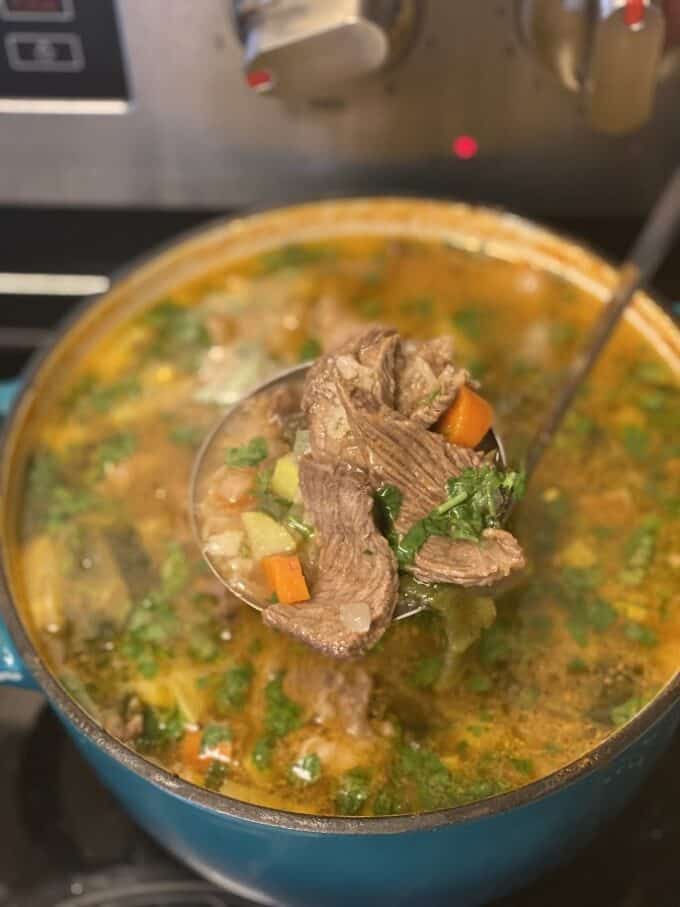 close up of beef and rice soup in ladle