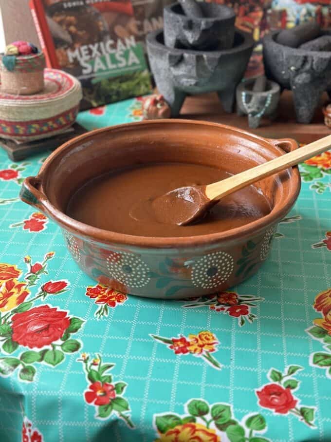 mole sauce in a Mexican cazuela with wooden spoon