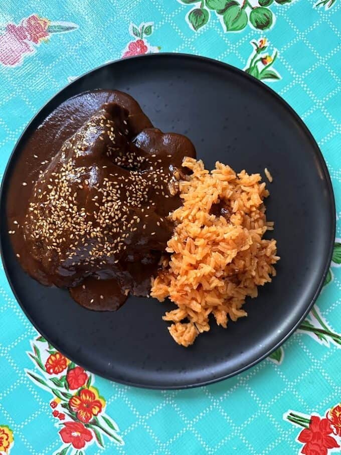 chicken mole served with Mexican rice, mole garnished with toasted sesame seeds