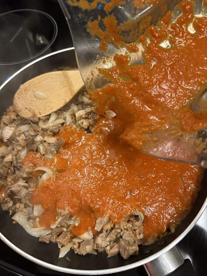 pouring blended red sauce into skillet with chicharron