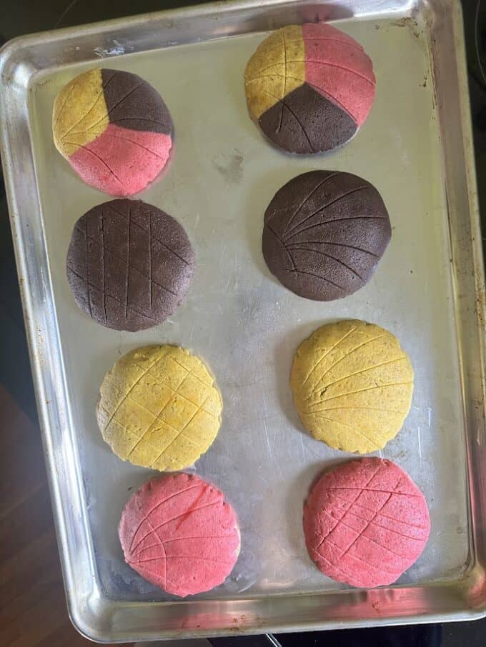 conchas with sugar topping in different colors on baking sheet