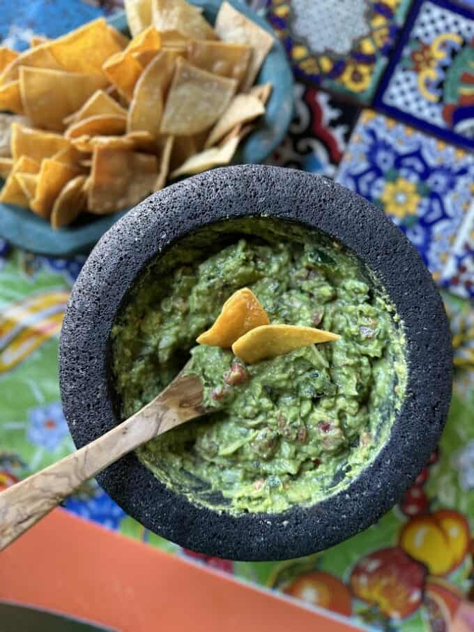 guacamole in molcajete with totopos in the back