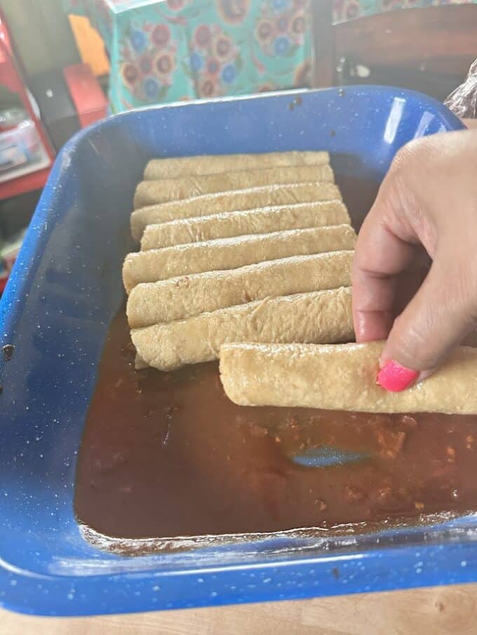 adding filled enchiladas to baking pan
