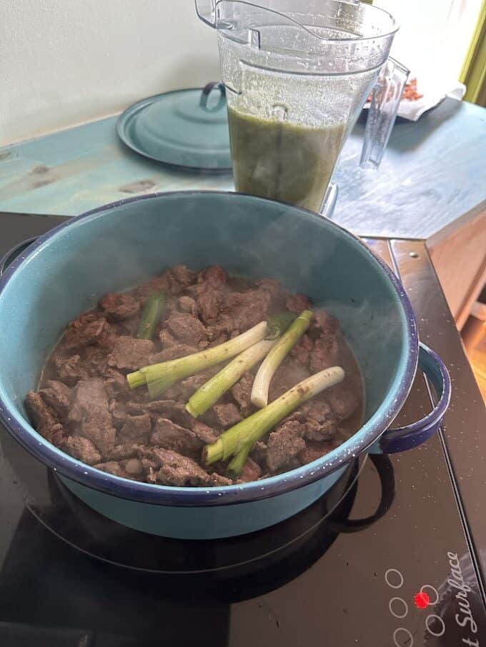 adding green onions and serrano peppers to the beef