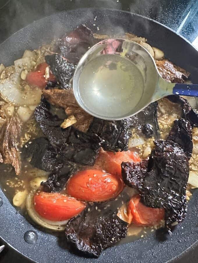 adding broth to pipian ingredients in the skillet