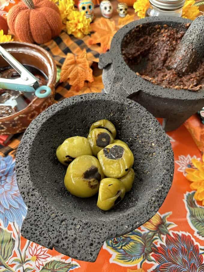 roasted tomatillos and crushed/ground chiles in two separate molcajetes