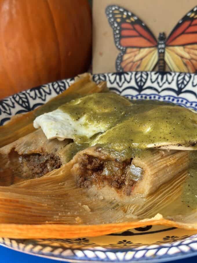 cooked tamales with beef filling, topped with a spicy salsa  verde and sunny side up eggs