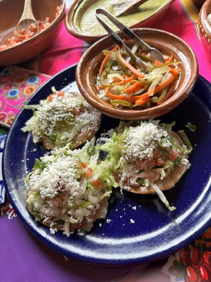 three loaded tostadas plated with escabeche on the side