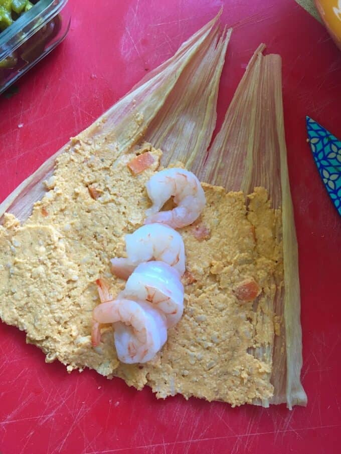adding shrimp to center of tamal