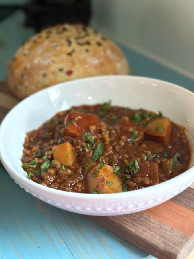 beef and barley stew plated with round loaf of bread