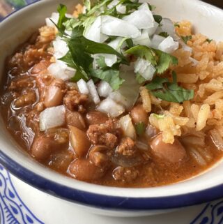 Arroz y frijoles in a bowl garnished with onion and cilantro