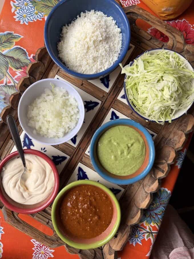 garnishes of cotija cheese, cabbage, onion, salsas and mexican crema