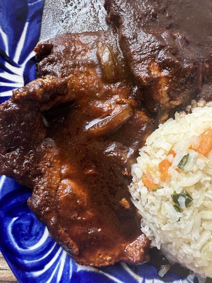 close up of pork chops in dark dried chile salsa